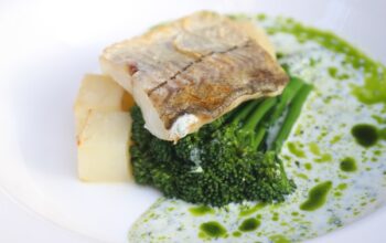 Zdjęcie przestawiające potrawę składającą się z ryby, brokułów i sosu podaną